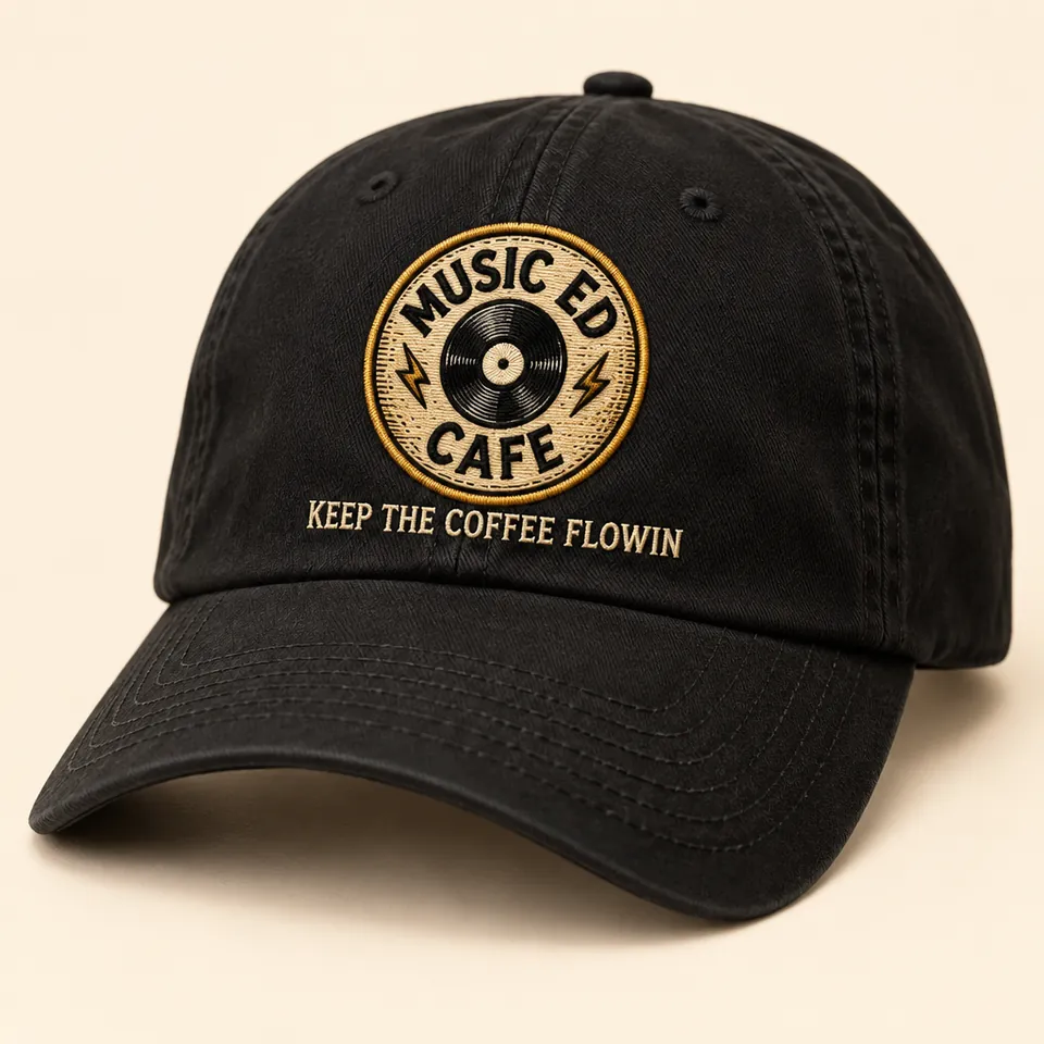 Mockup of a black dad hat embroidered with the Music Ed Cafe record badge and the words Keep the Coffee Flowin